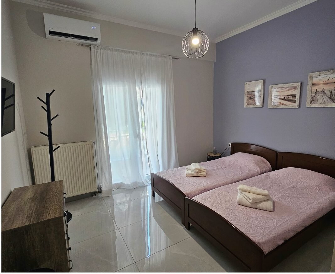 Bright second bedroom with two single beds, air conditioning, large wardrobes and balcony access