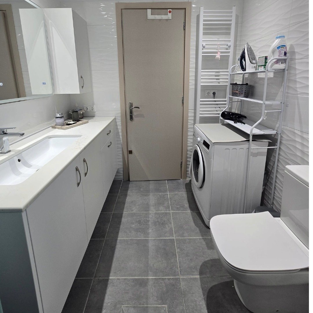 Bathroom with washing machine, toilet, vanity and storage